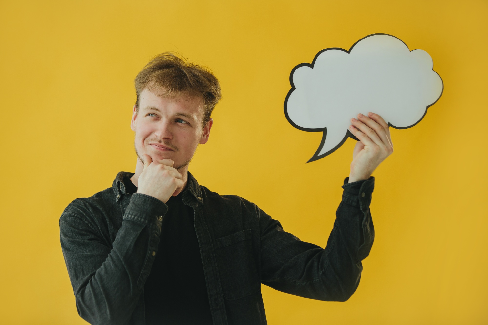 Man Holding a Speech Bubble on Yellow Background Expressing Curiosity