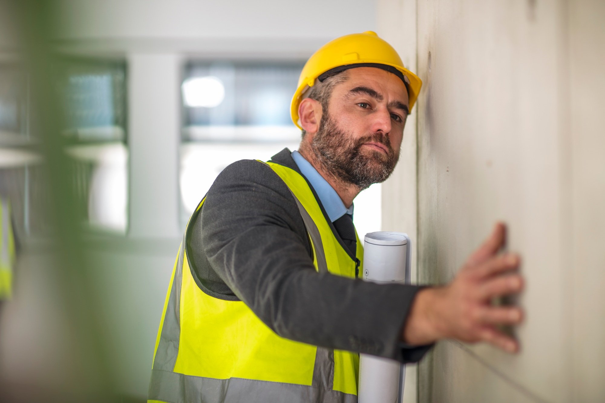 Man holding blueprint surveying wall