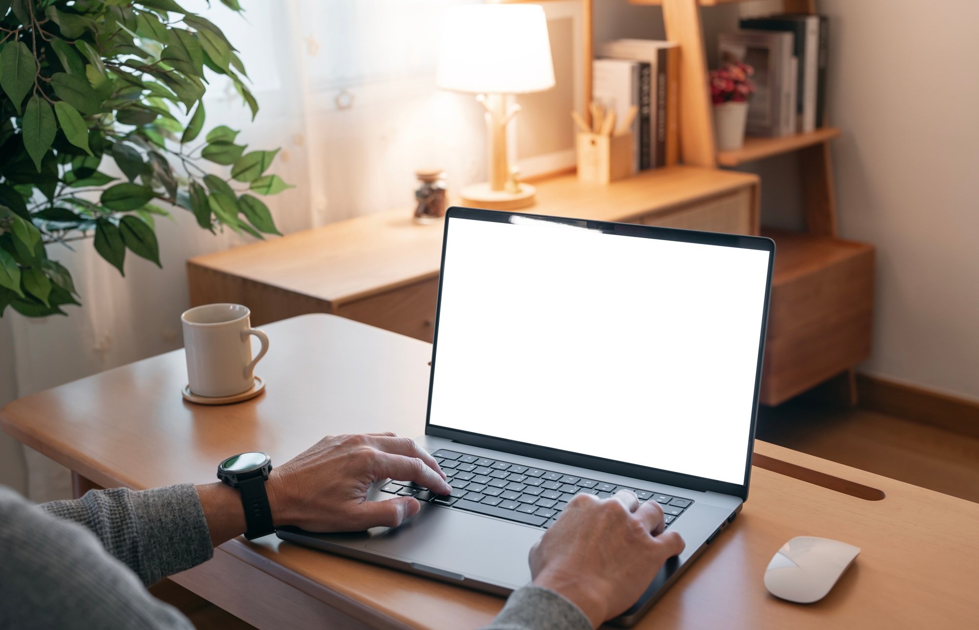 man working on laptop computer at a table, typing on the laptop keyboard.