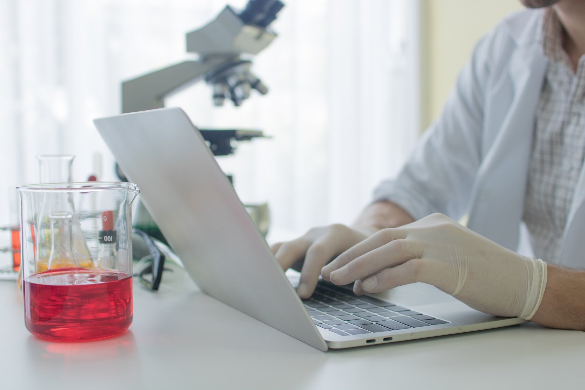 medical technician or researcher writing and search information on laptop in medical laboratory