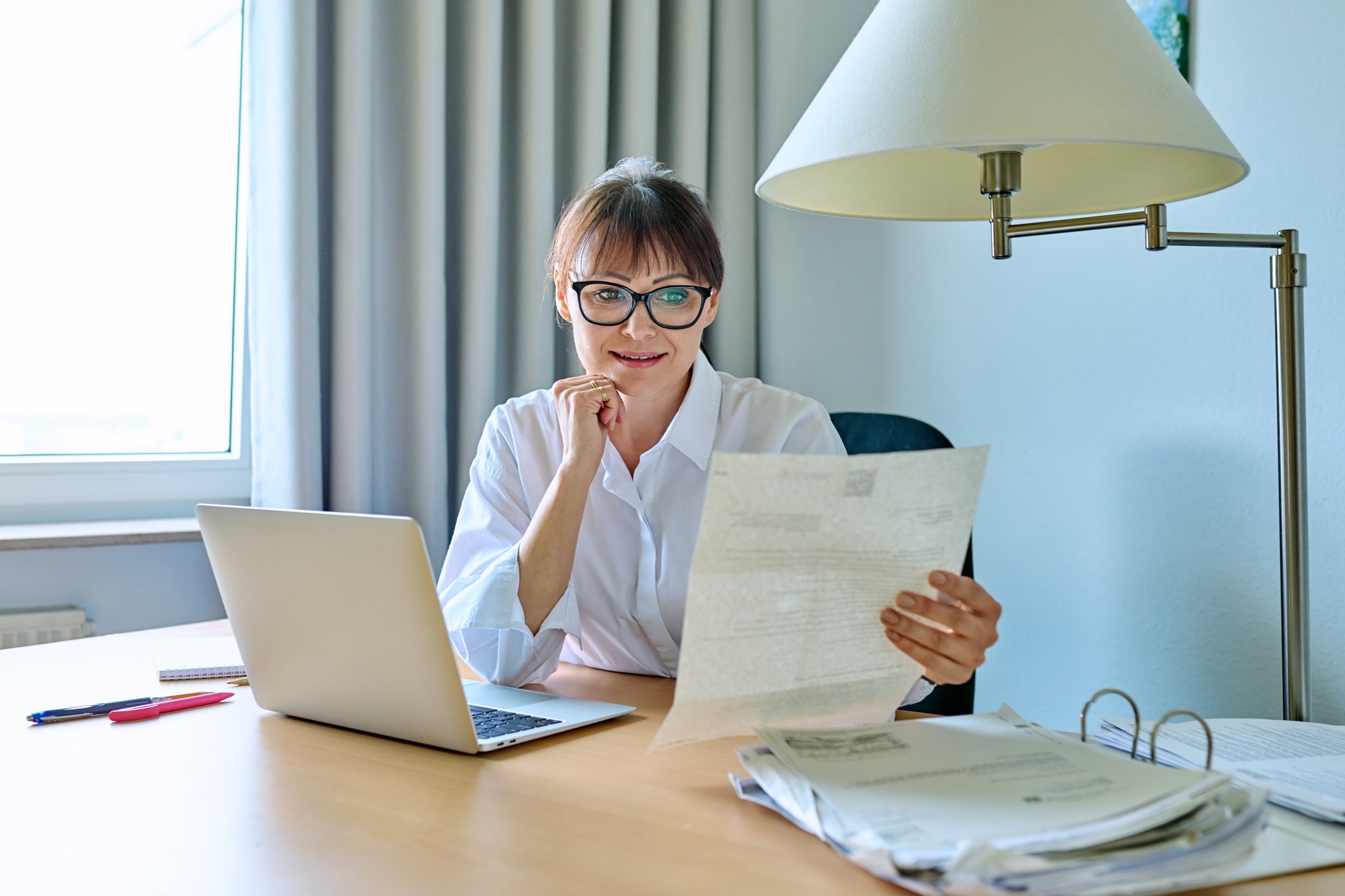 Middle aged businesswoman reading business official paper letter document