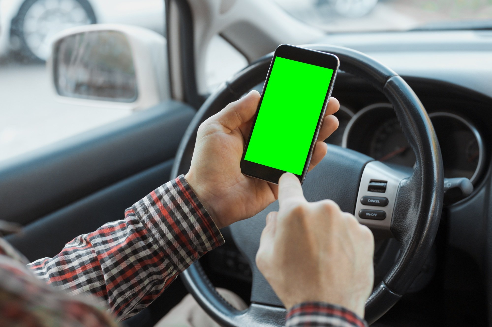 Millennial man using app on mobile phone with chroma key in car