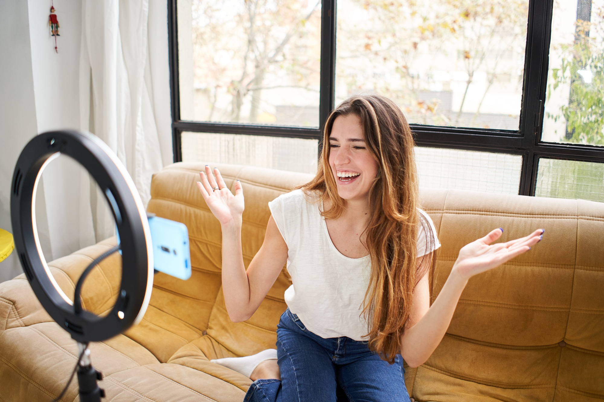 Modern influencer. Female vlogger making social media video while sitting indoors sofa