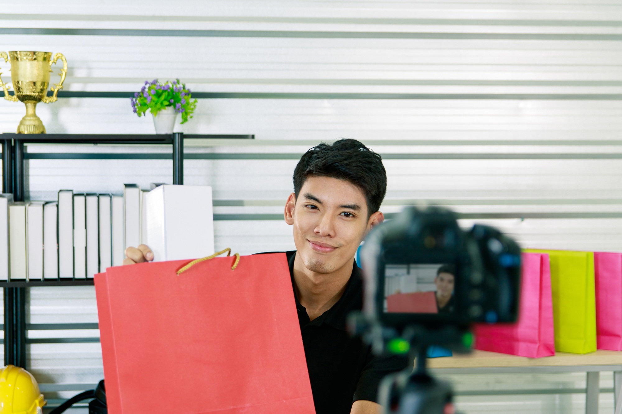 Online blogger, Asian man, uses a smartphone to record live video vlog to present productsf