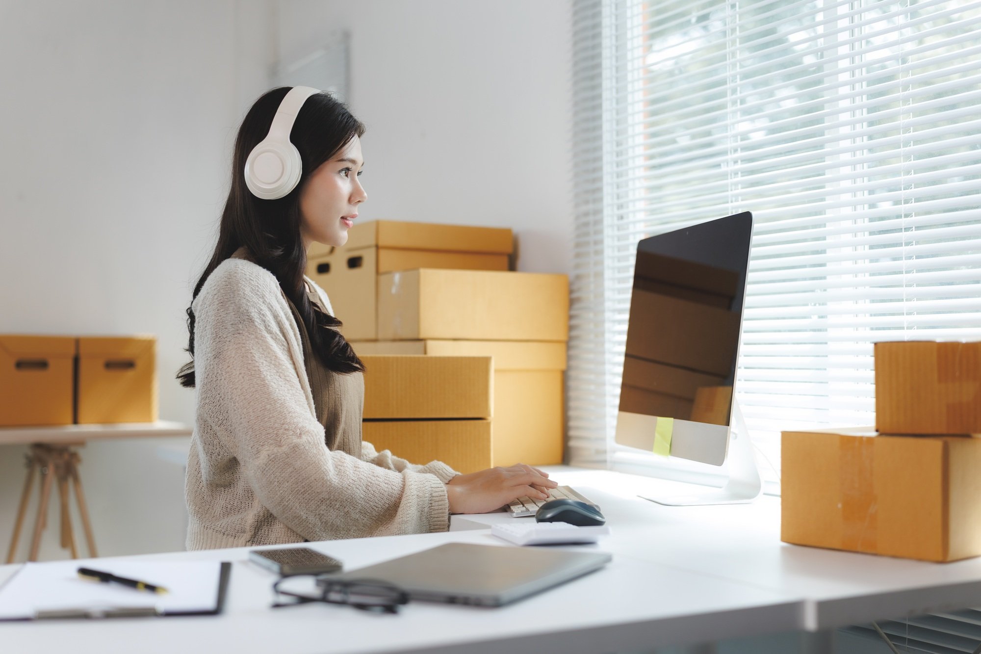 Online seller working with headphones in warehouse office