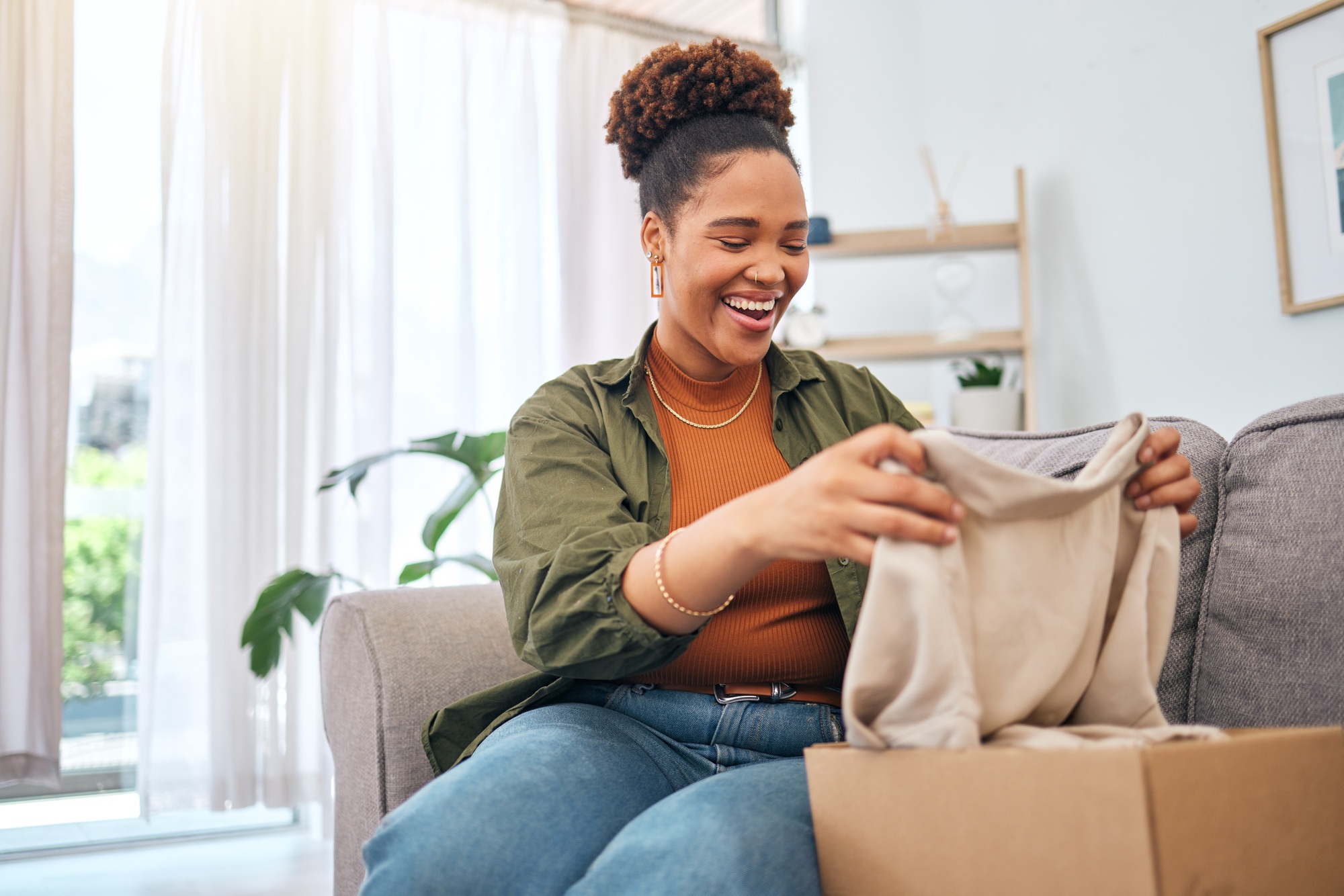 Online shopping, happy woman on sofa with package unboxing, discount fashion retail gift in living