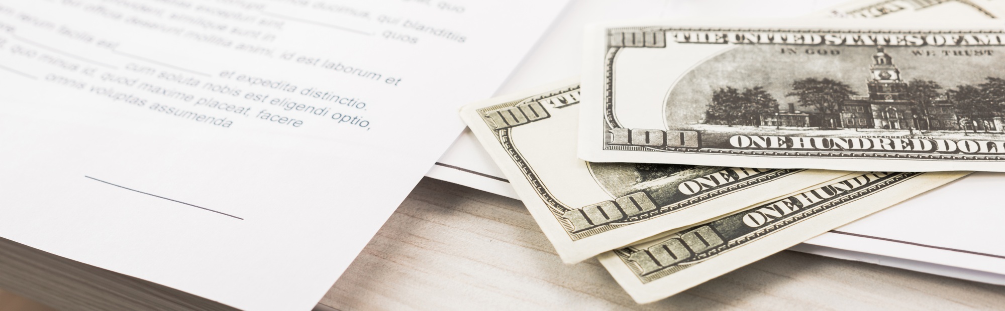 panoramic shot of dollar banknotes near documents and pen on desk
