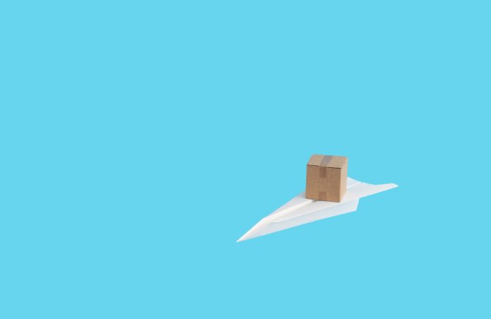 Paper plane with a cardboard package on it, shipping and delivery service concept