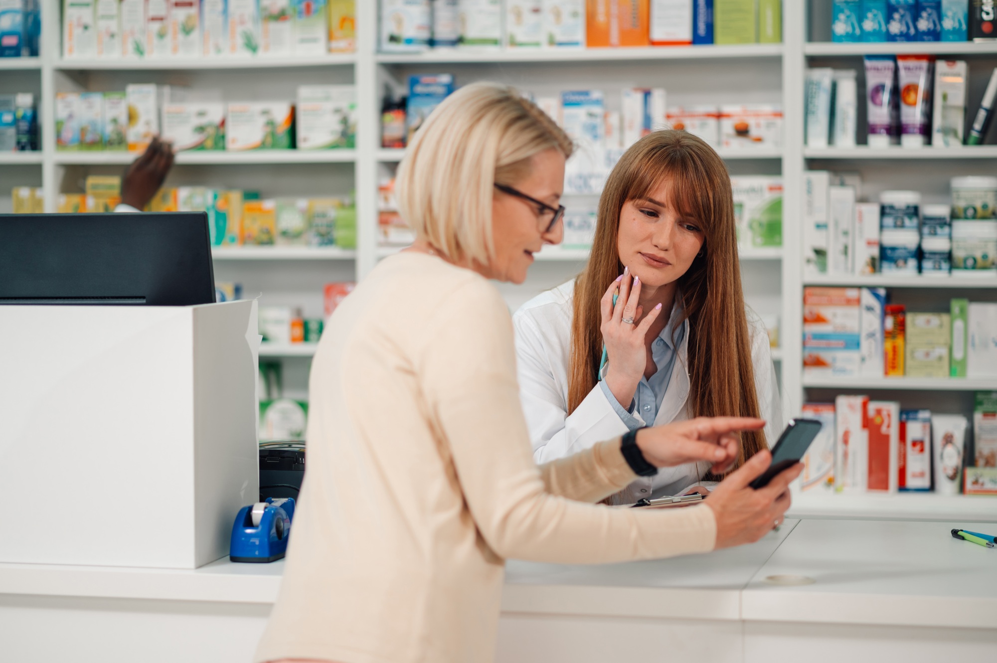 Pharmacist meeting senior woman's needs at pharmacy shop.