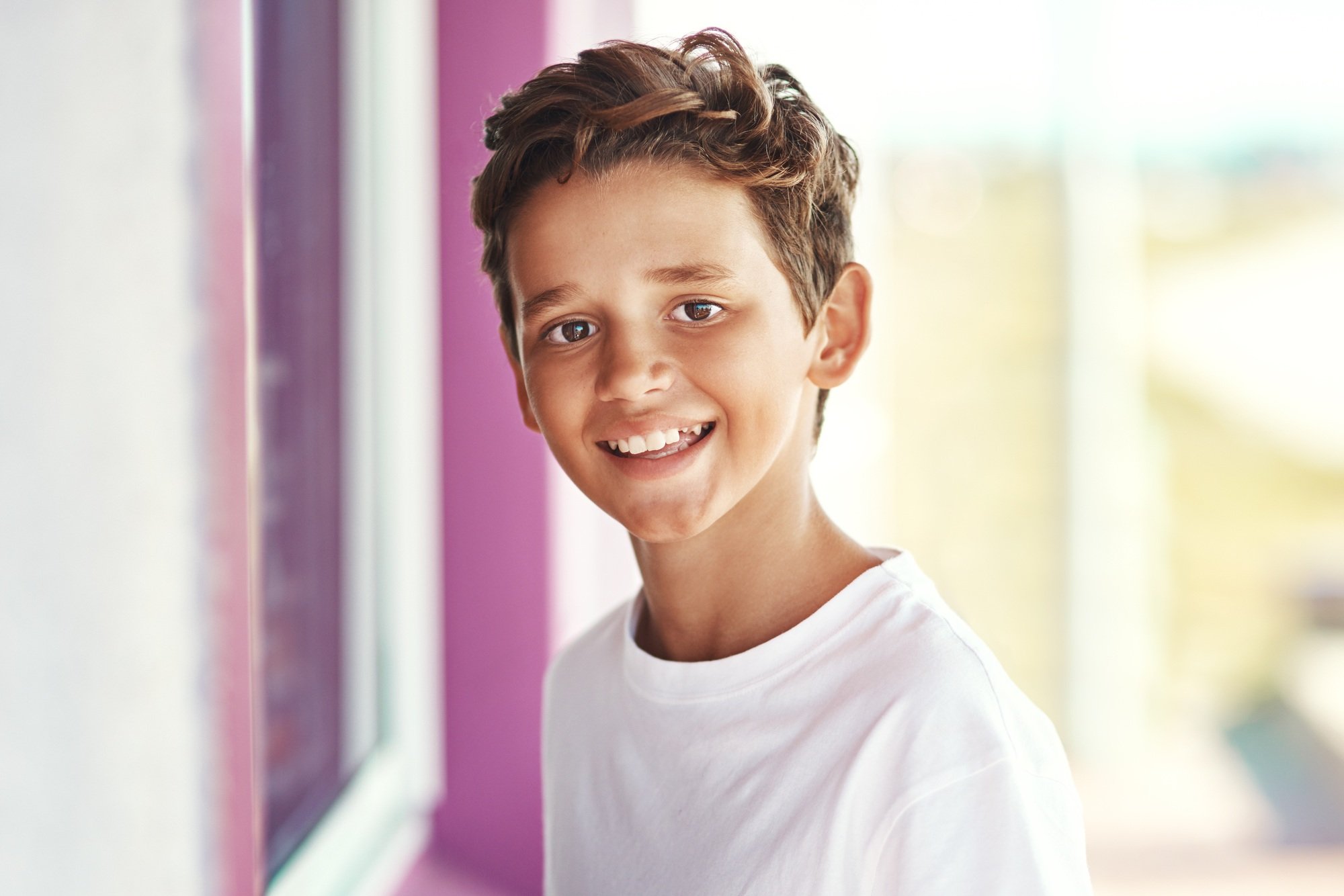 Portrait of a cheerful little boy standing outside an ice-cream shop by the beach