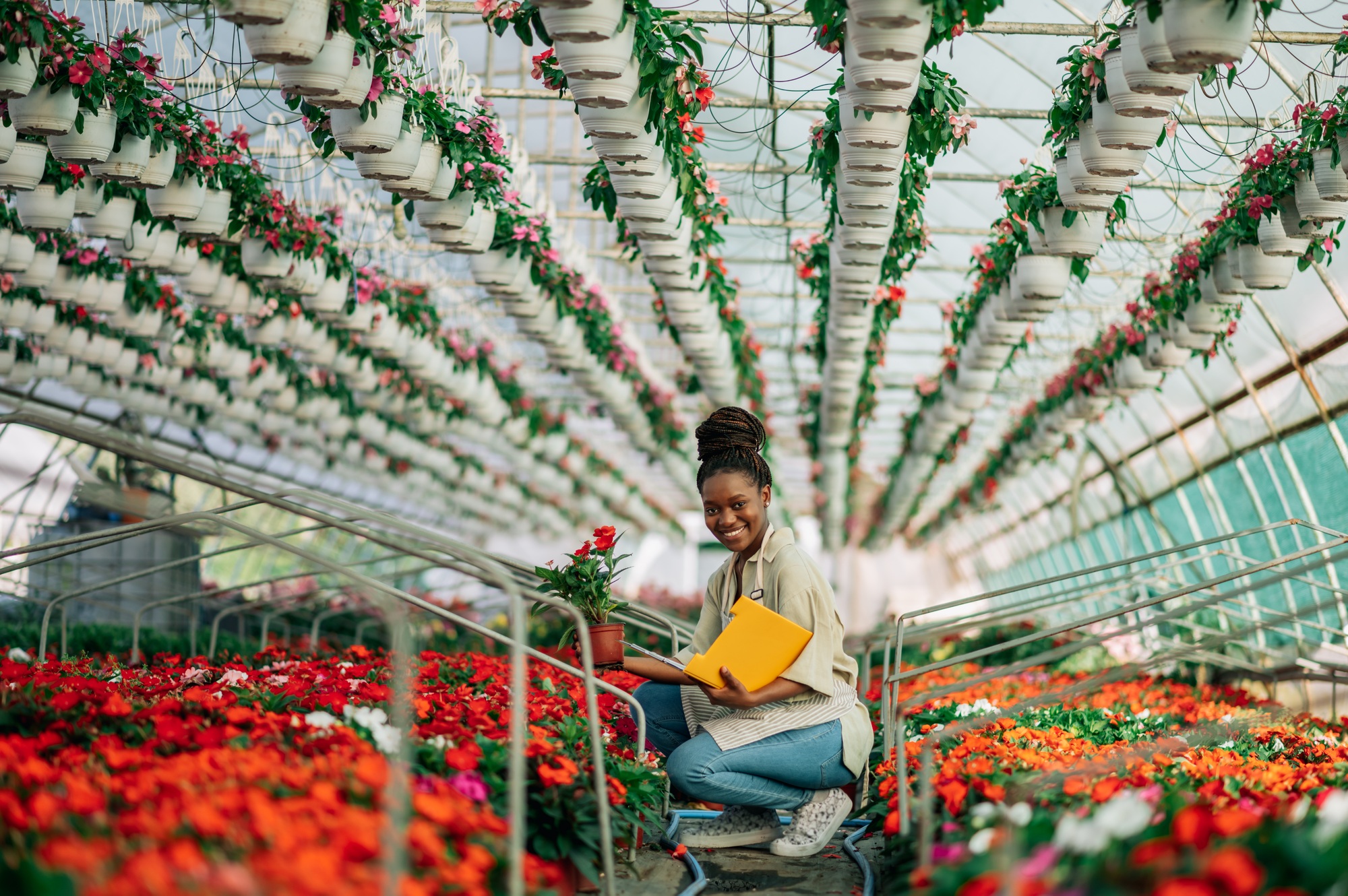 Portrait of a young black woman at work in greenhouse wearing uniform. Copy Space