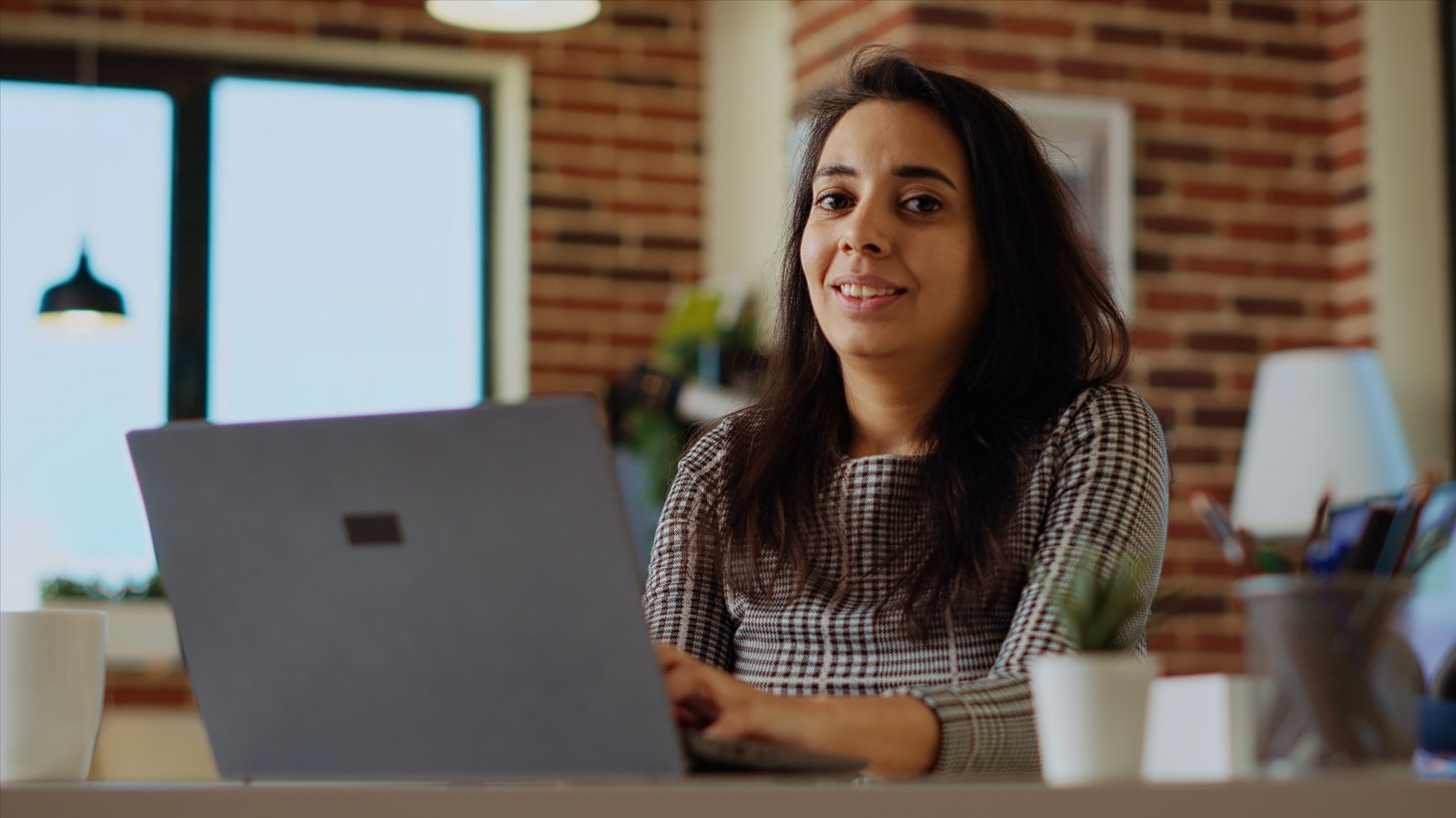 Portrait of cheerful freelancer checking her emails on notebook device
