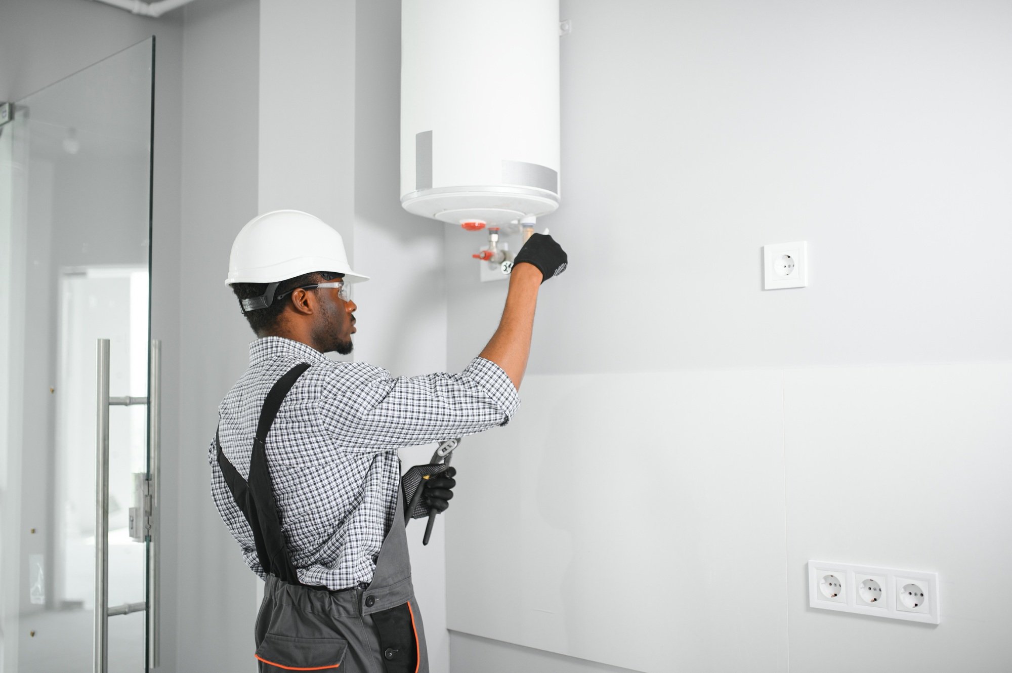 Professional african american engineer doing a boiler inspection at home