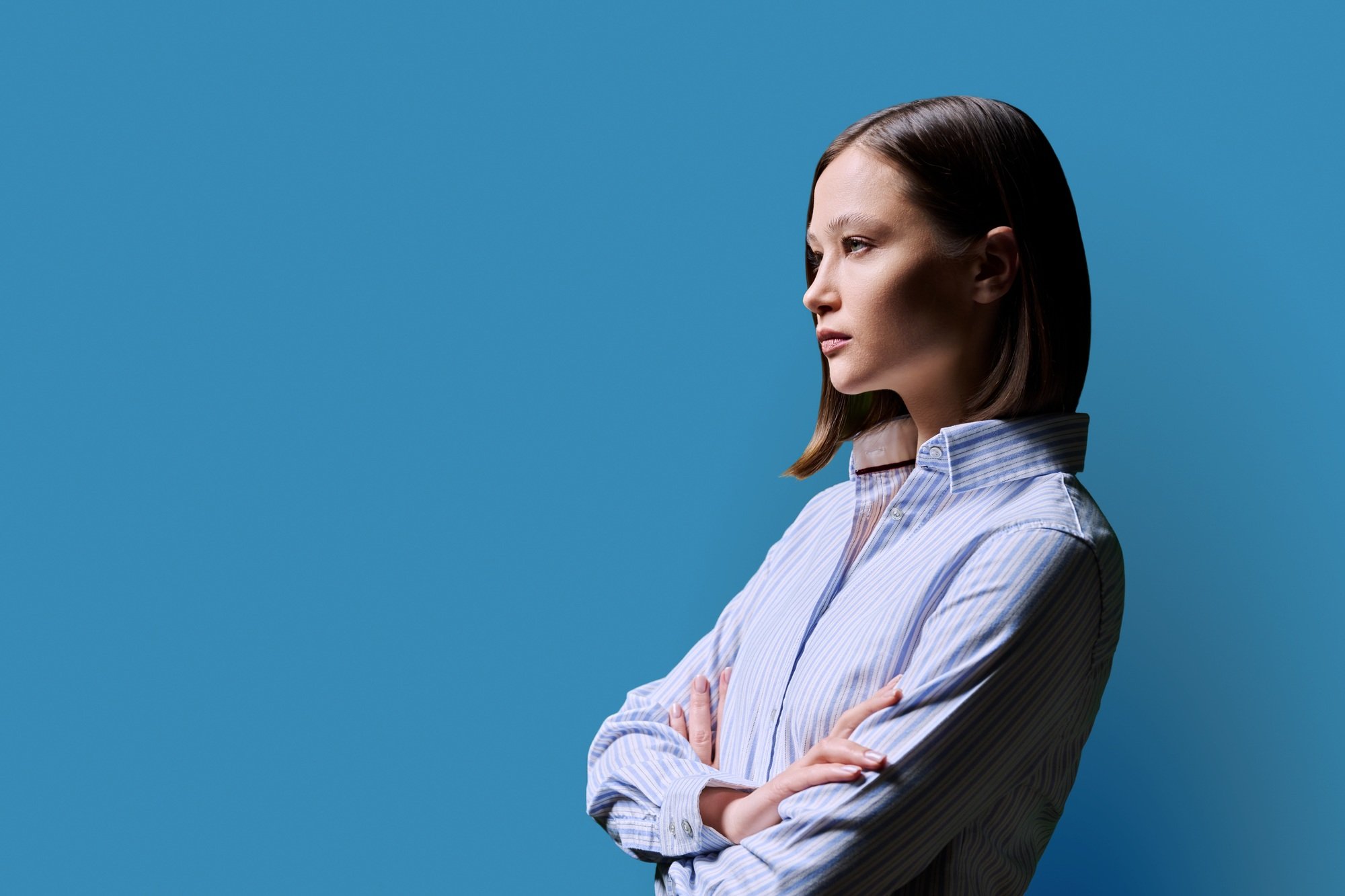 Profile view, confident young business woman, copy space blue background