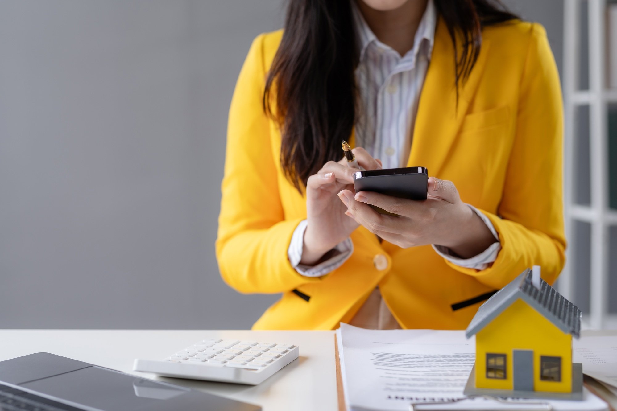 Real estate agent woman with a smile using smartphone at the office.