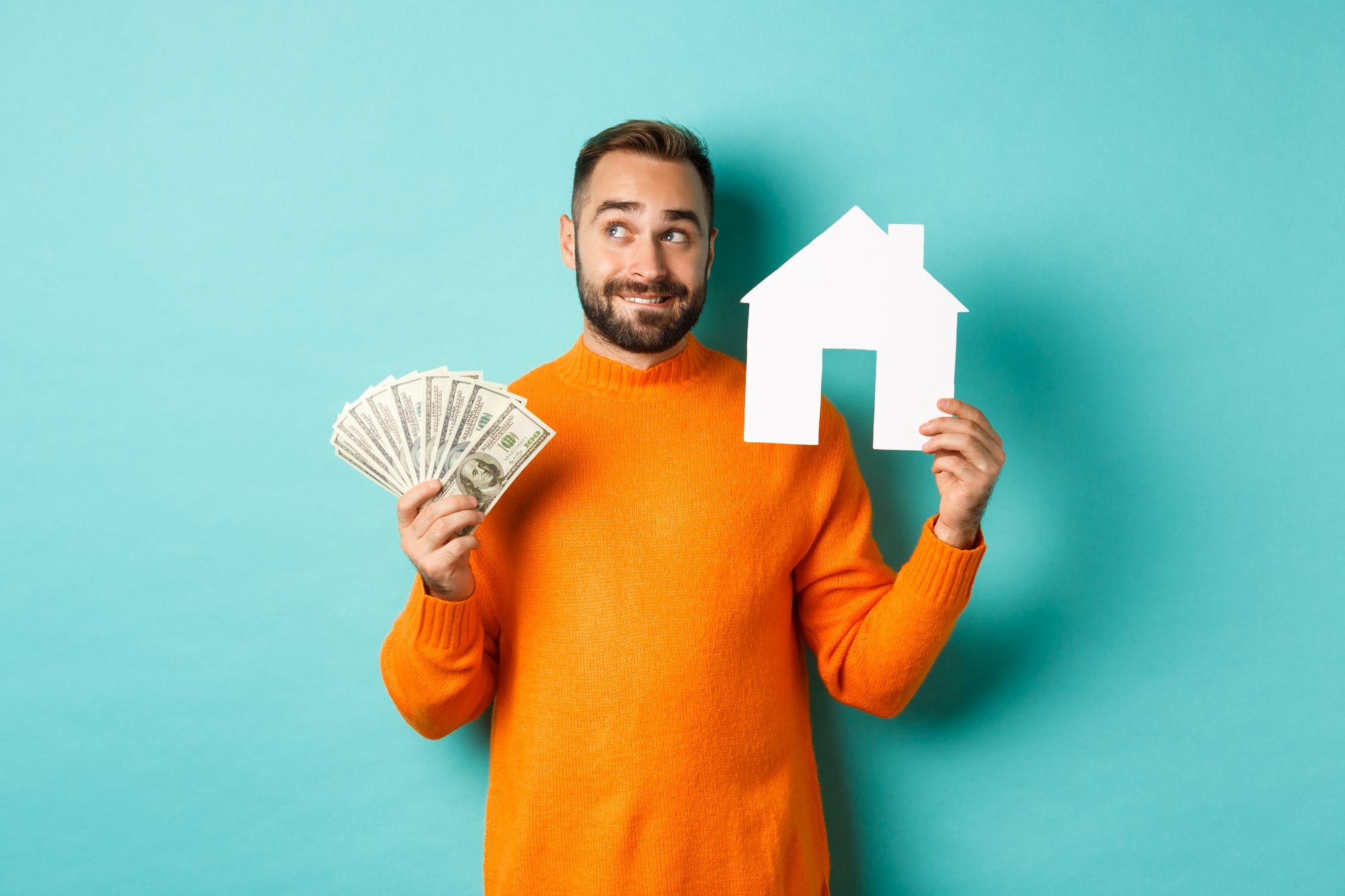 Real estate concept and mortgage concept. Handsome young man buying house, holding home maket and