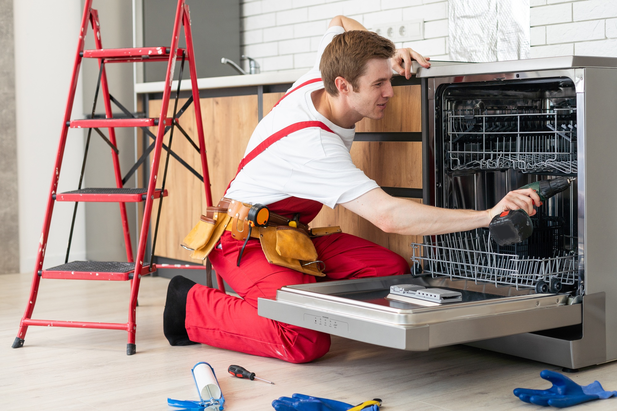 Repair of dishwashers. Repairman repairing dishwasher in kitchen