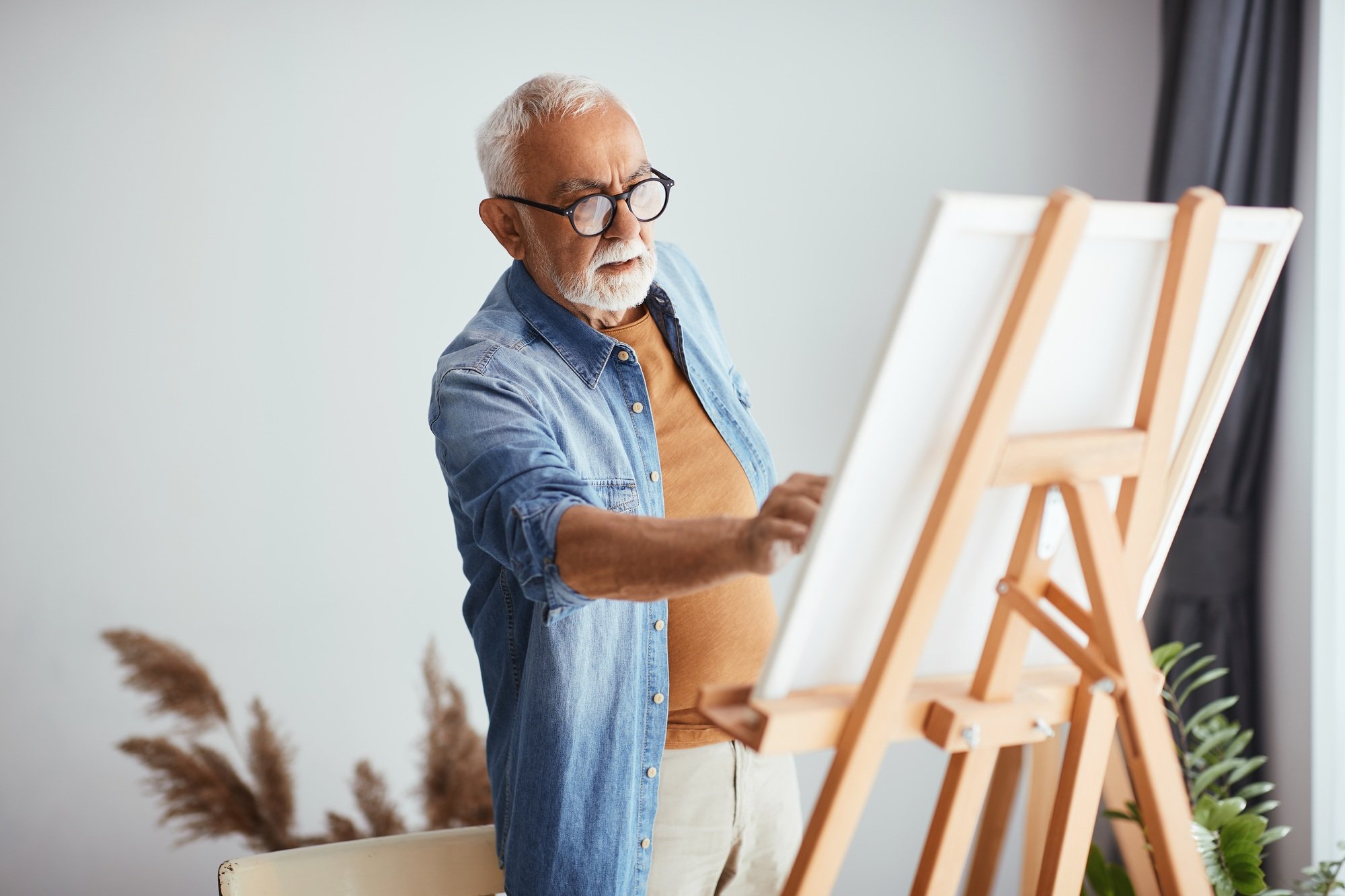 Senior artist painting on canvas at home studio.