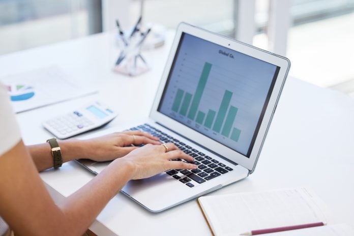 Shot of a businesswoman using her laptop to compile spreadsheets