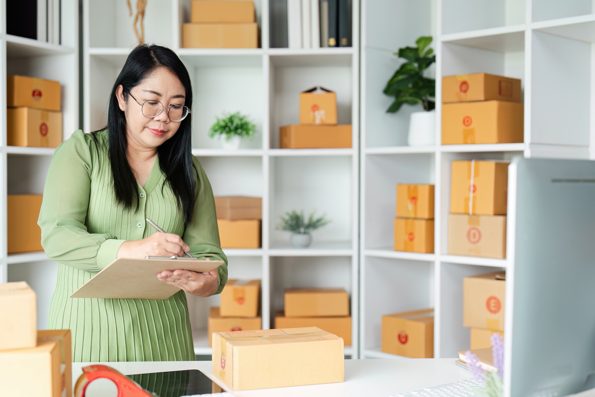 Small Business Owner Managing Inventory in a Modern Home Office with Shipping Boxes and Supplies