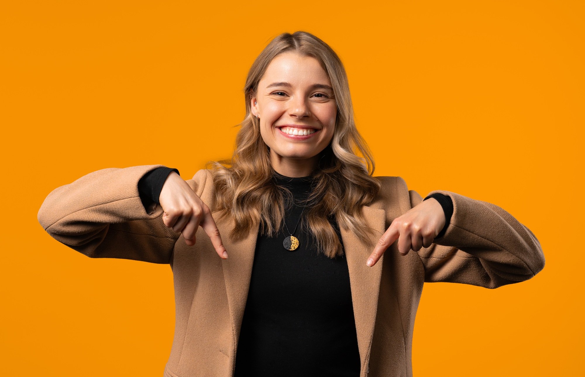 Smiling businesswoman pointing down advertising area on yellow. Click subscribe