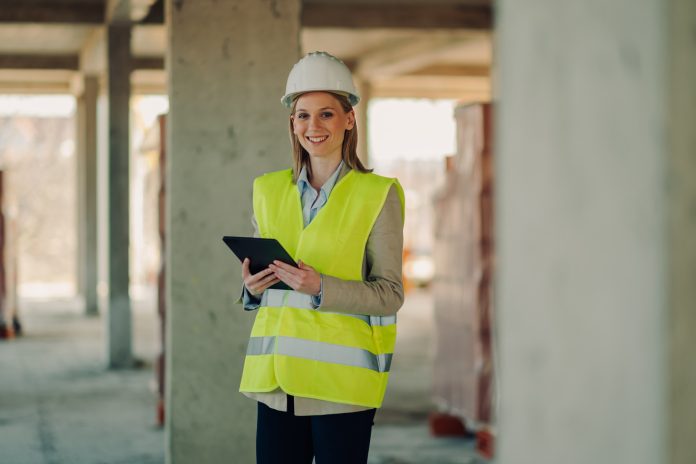 Smiling female engineer using digital tablet at construction site