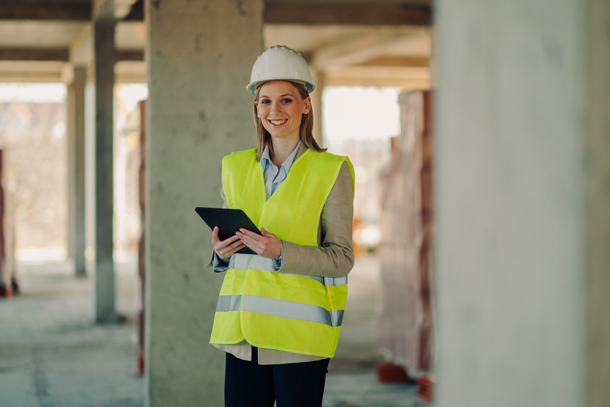 Smiling female engineer using digital tablet at construction site