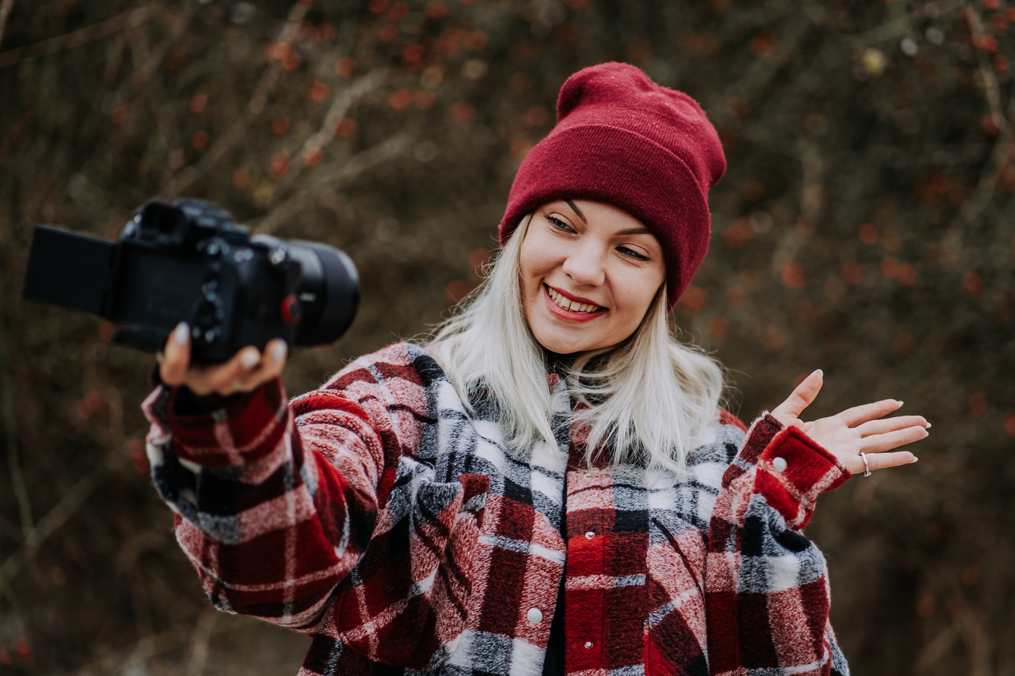Smiling travel blogger woman making new video blog, vlog, with her camera on nature forest backgroun
