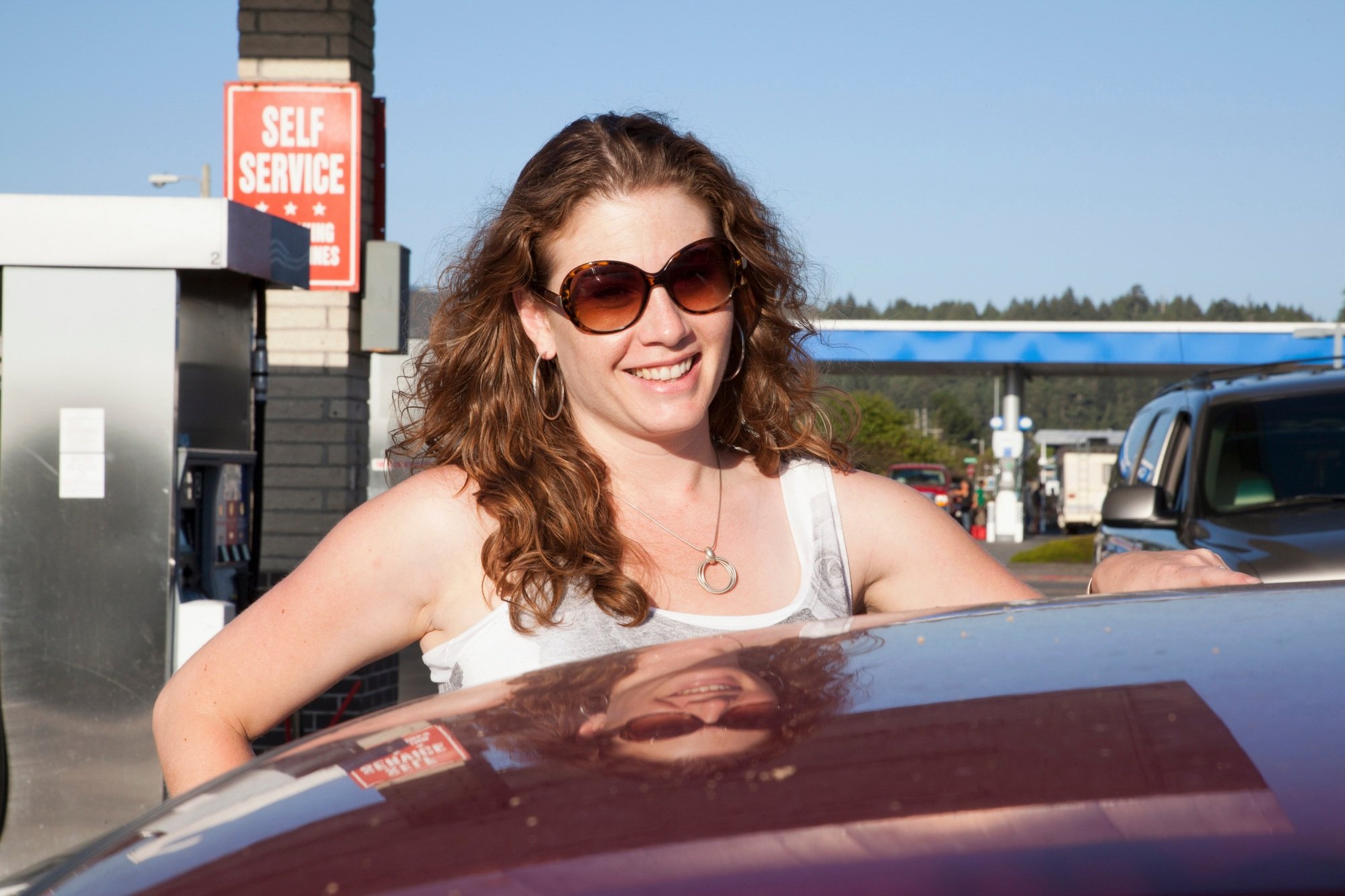 Smiling woman pumping gas at station