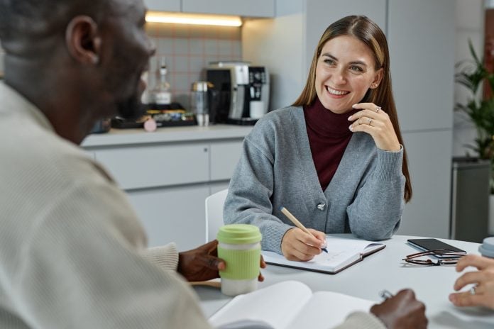 Smiling Woman Talking Shop with Male Colleague Discussing Business Plan at Cafe Table