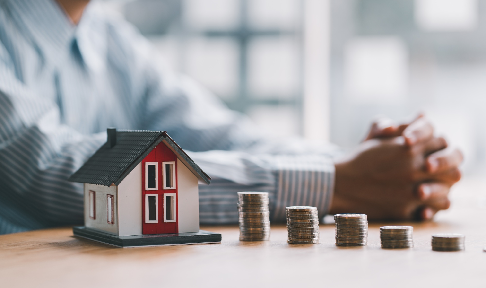 stack of money and home models, home insurance ideas and insurance agents for those interested.