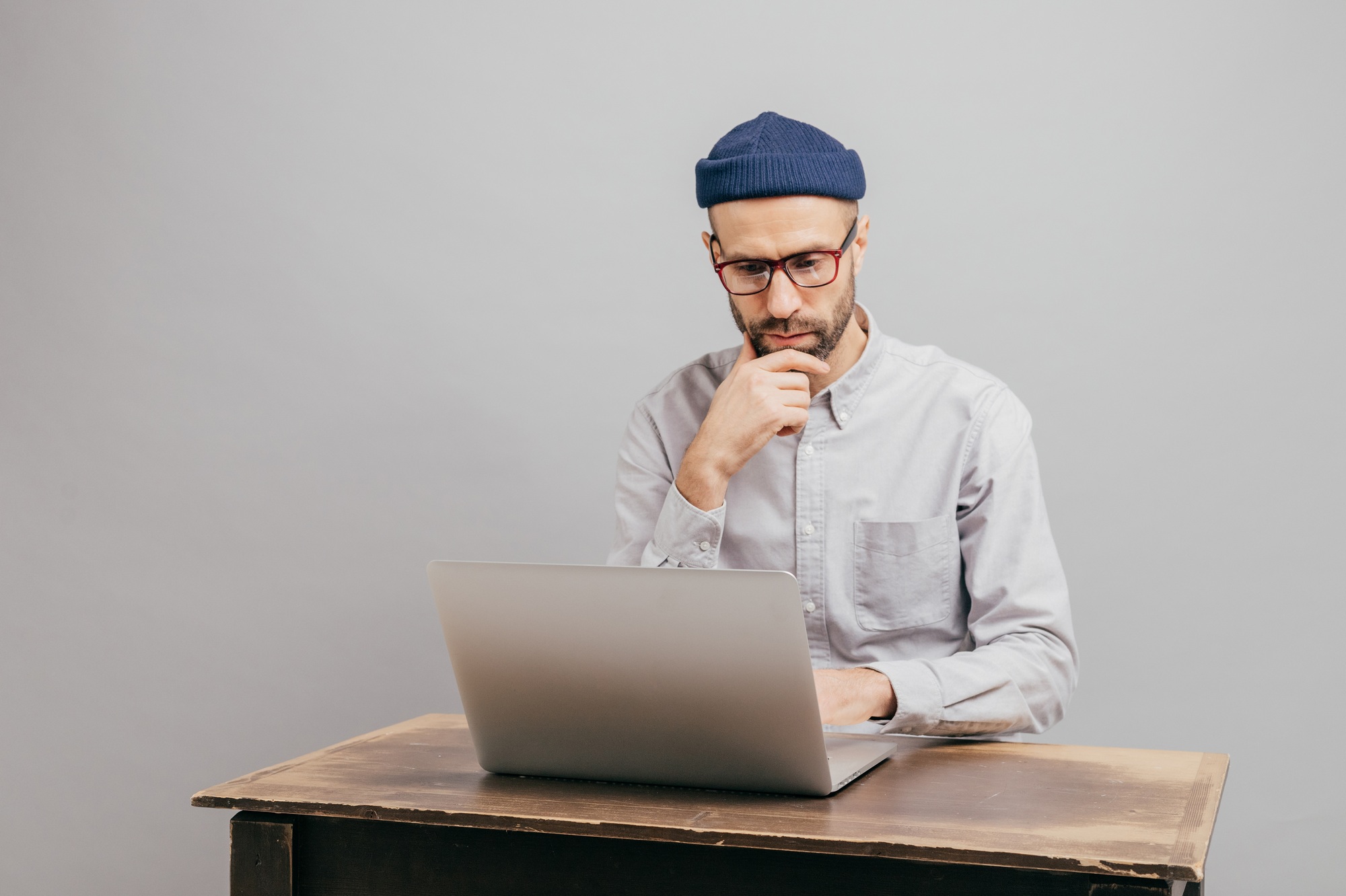 Successful male designer keyboards on laptop computer, checks database