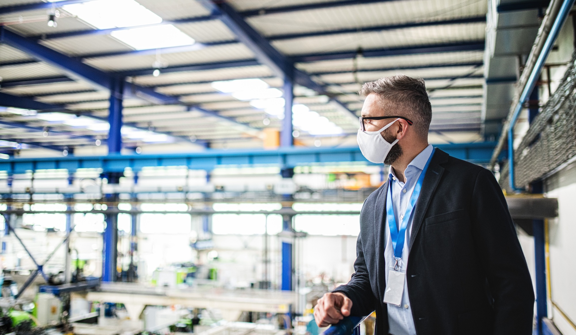 Technician or engineer with protective mask standing in industrial factory