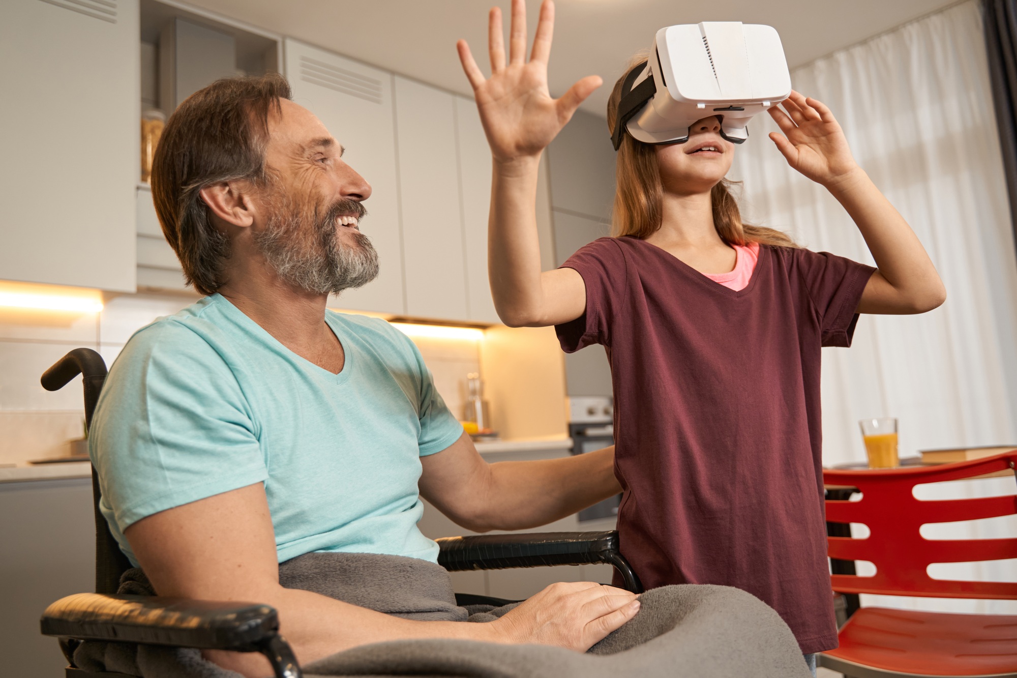 Teenager stands in virtual reality glasses near man in wheelchair