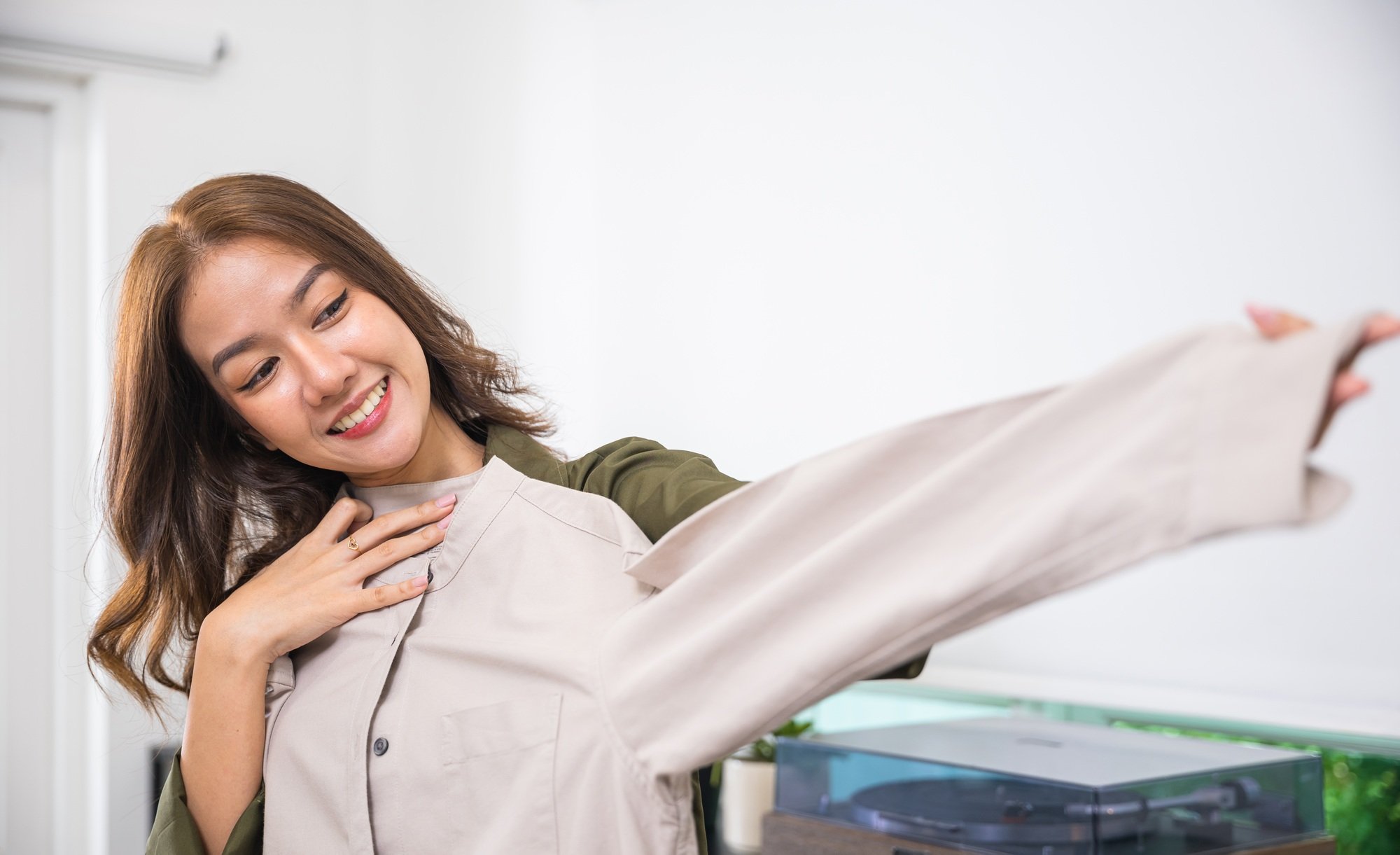 The woman in the image is smiling and appears to be admiring a piece of clothing. She looks happy