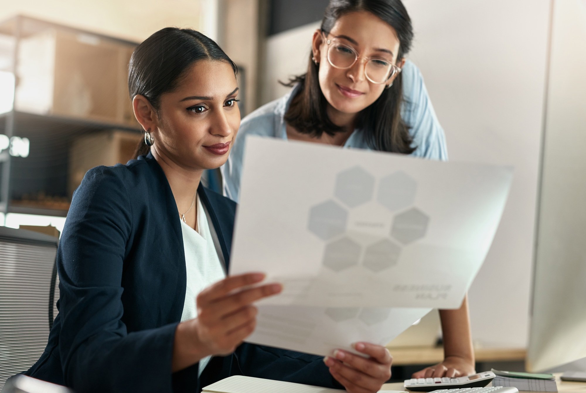 This report has some great data. Shot of two female coworkers surveying paperwork.