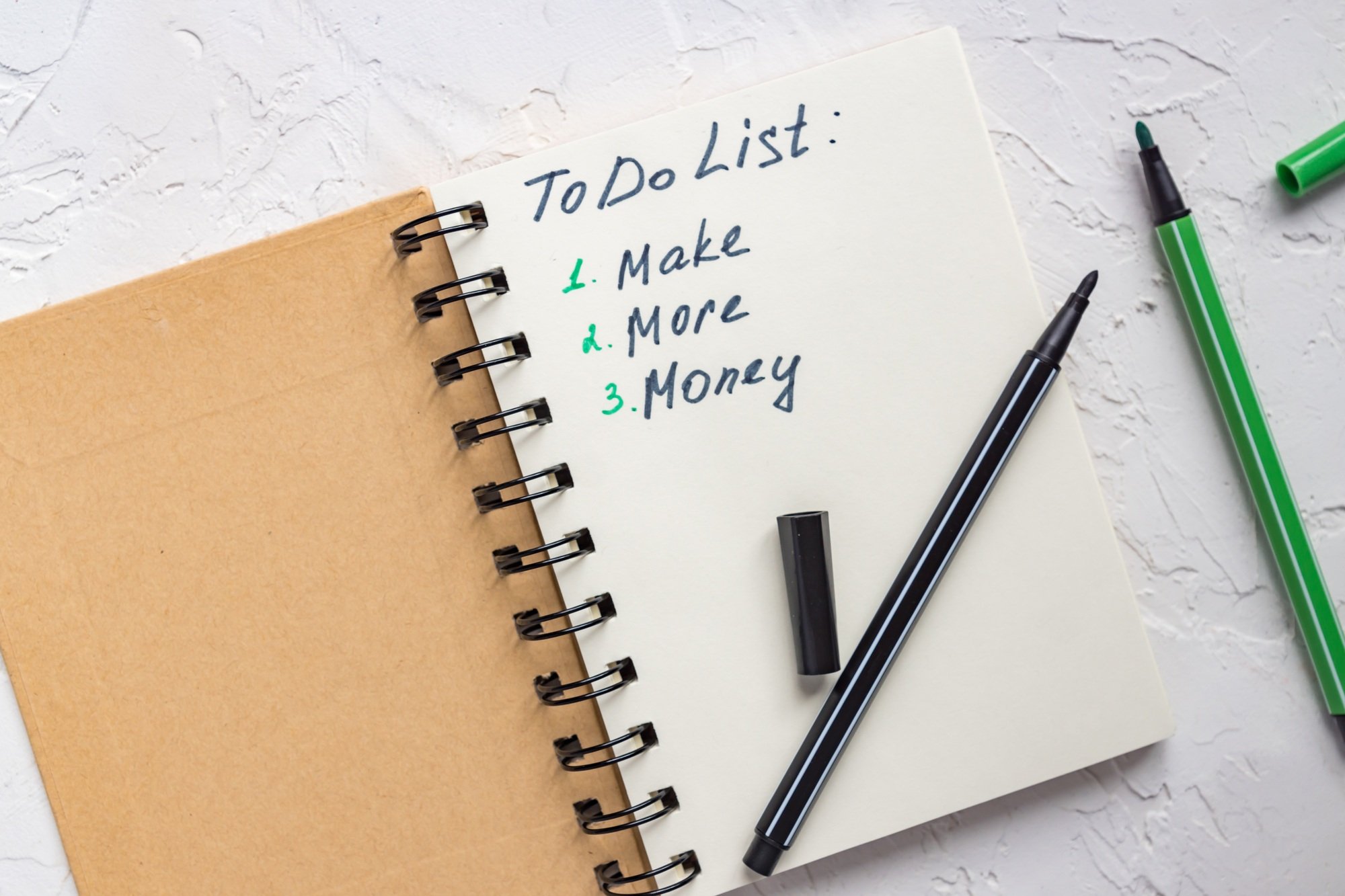 To do list. Make more money. Open notebook with motivation quote and felt tip pens. Top view