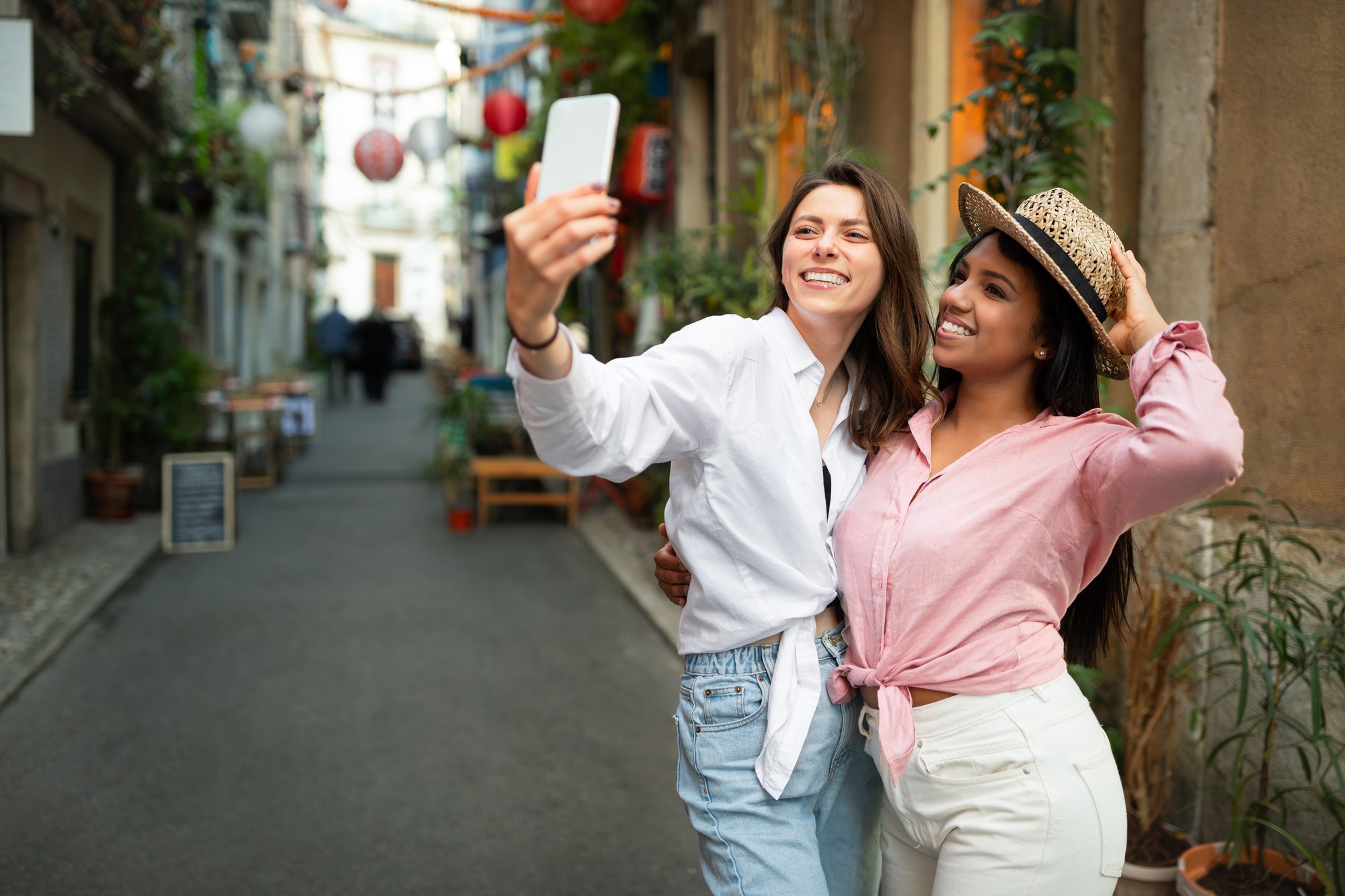 Video call, blog. Happy young millennial international women tourists in hat make selfie on phone