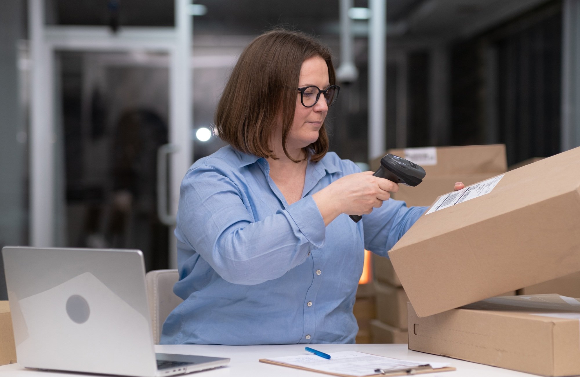 Woman barcode scanner in office online marketplace: dropshipping business laptop, shipping boxes