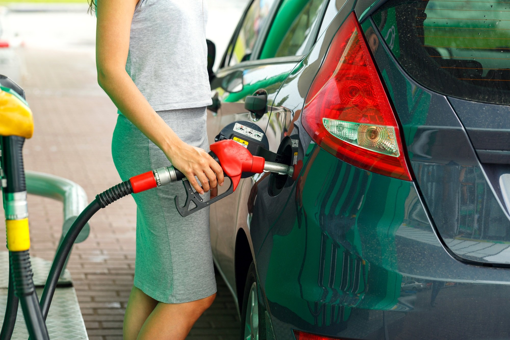 Woman fills petrol into the car at a gas station