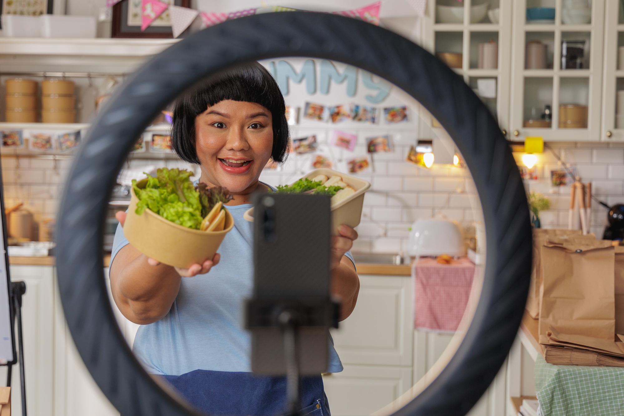 Woman Live Streaming in Kitchen Holding Fresh Food Bowls for Online Restaurant Promotion