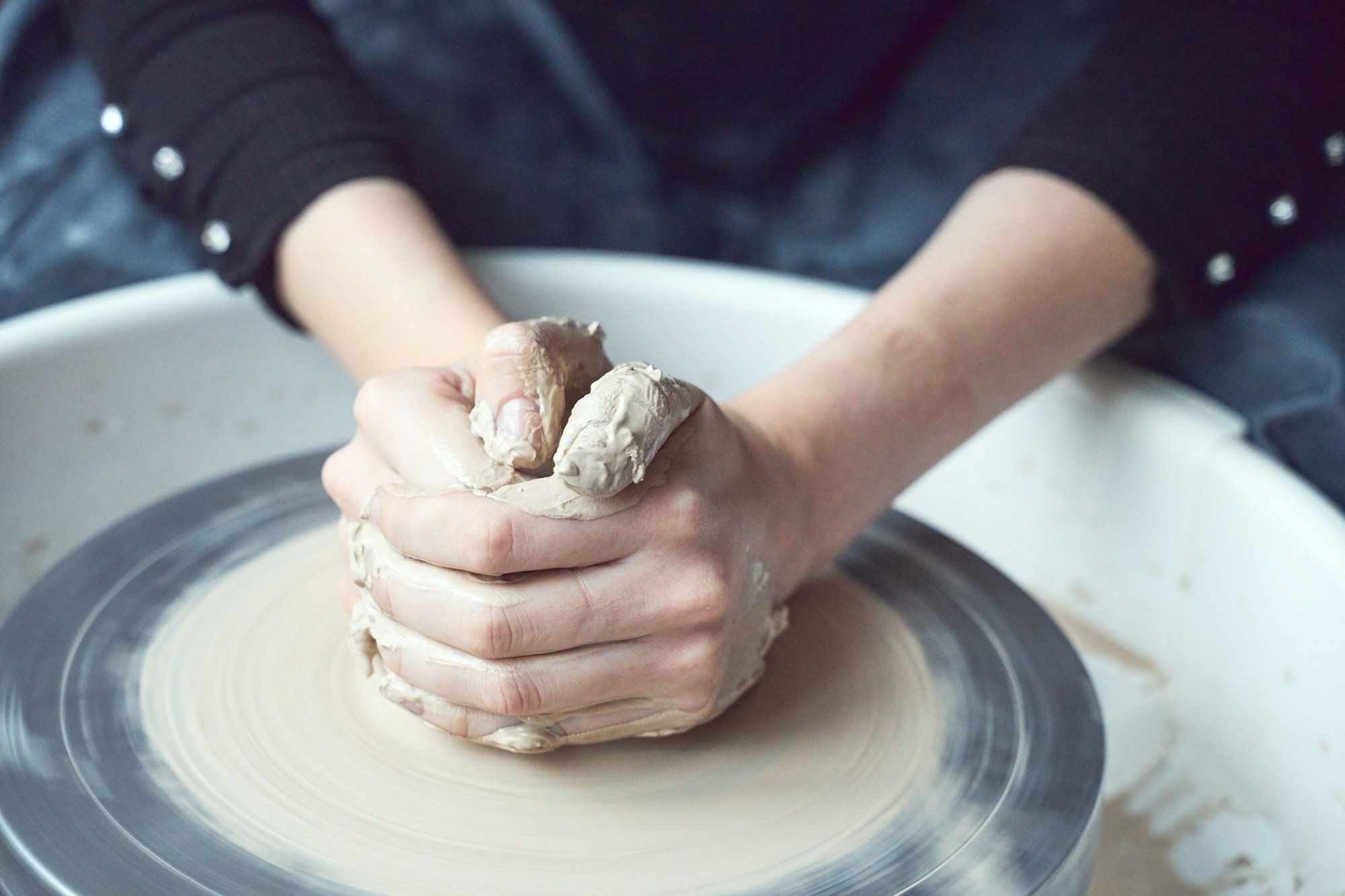 Woman making ceramic pottery on wheel, hands close-up