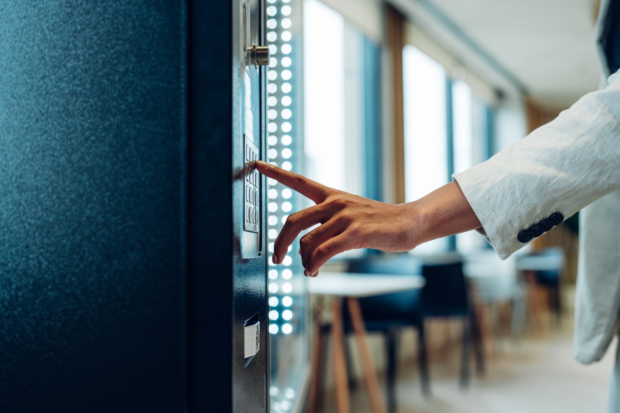 woman's finger pushing number button on keyboard of snack vending machine.