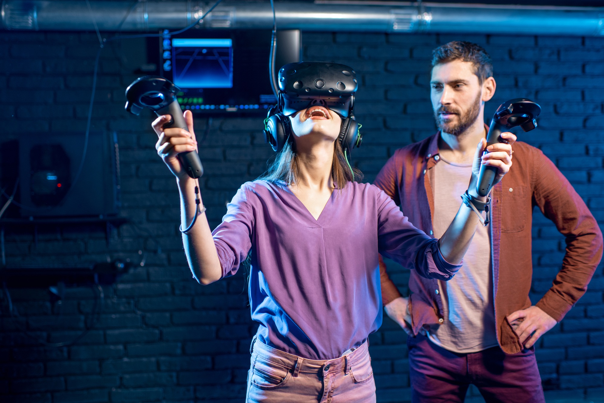 Woman trying virtual reality with man assistant