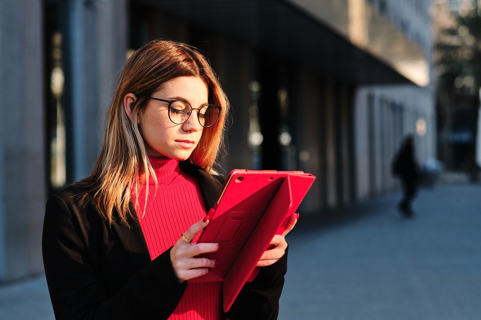Woman using a digital tablet while standing outdoors.
