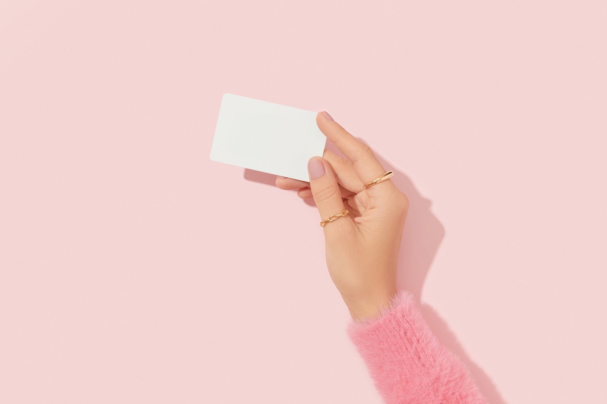 Womans hand touch a white blank business card that floats on a pink background