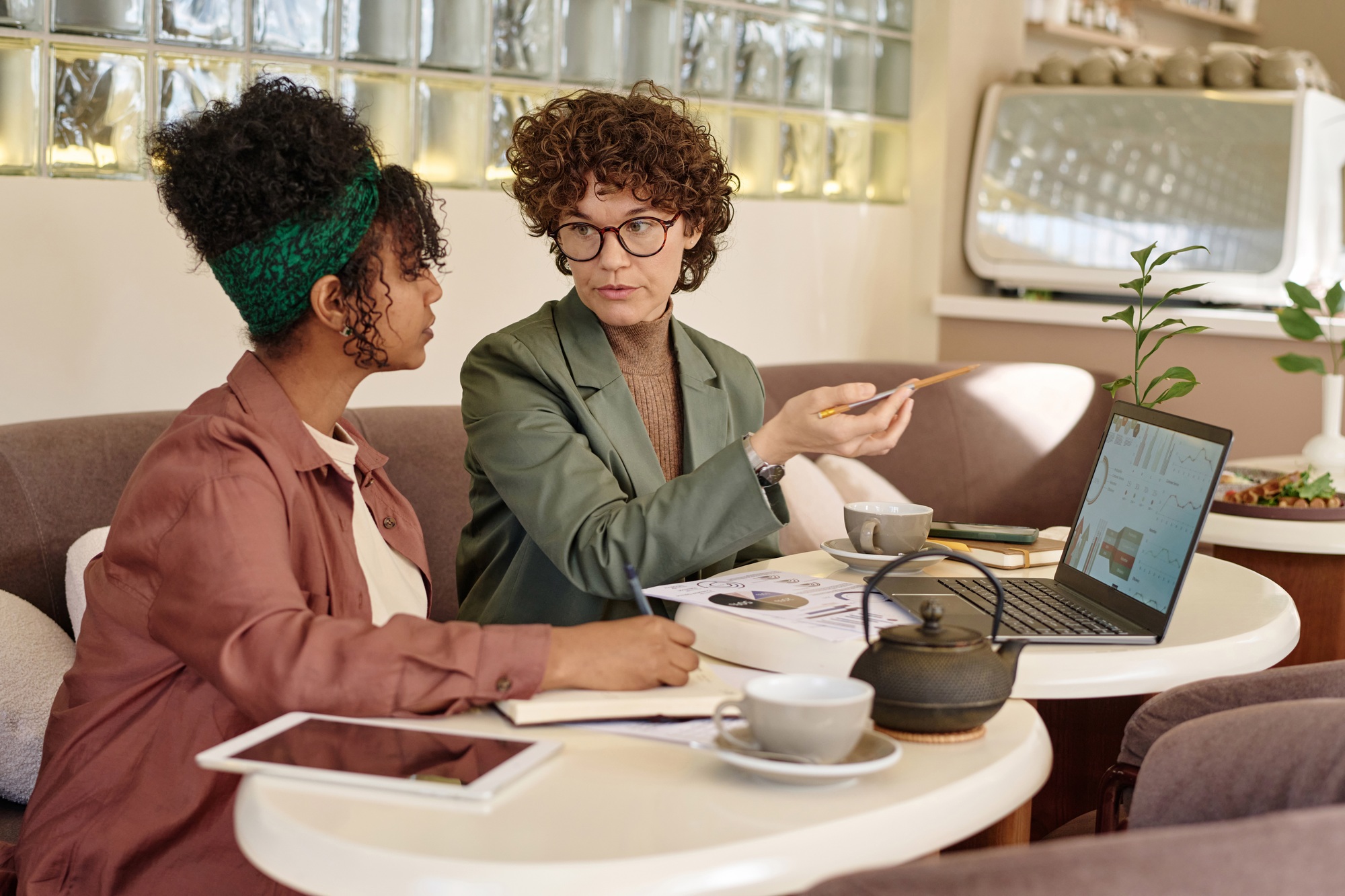 Women Discussing Graphs and Charts Sitting at Local Cafe