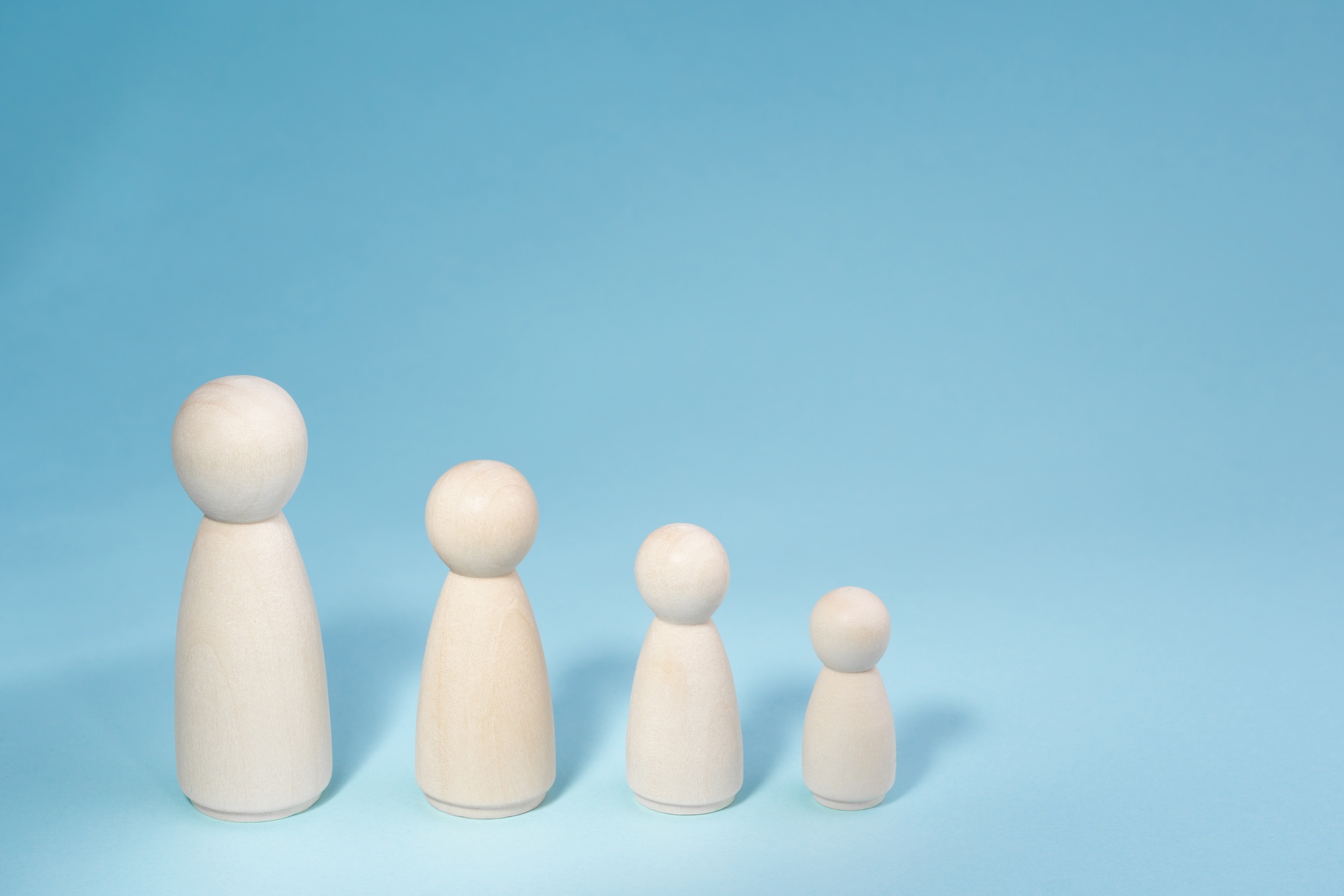 Wooden figurines standing in a row from high to low. Concept person growth on blue background