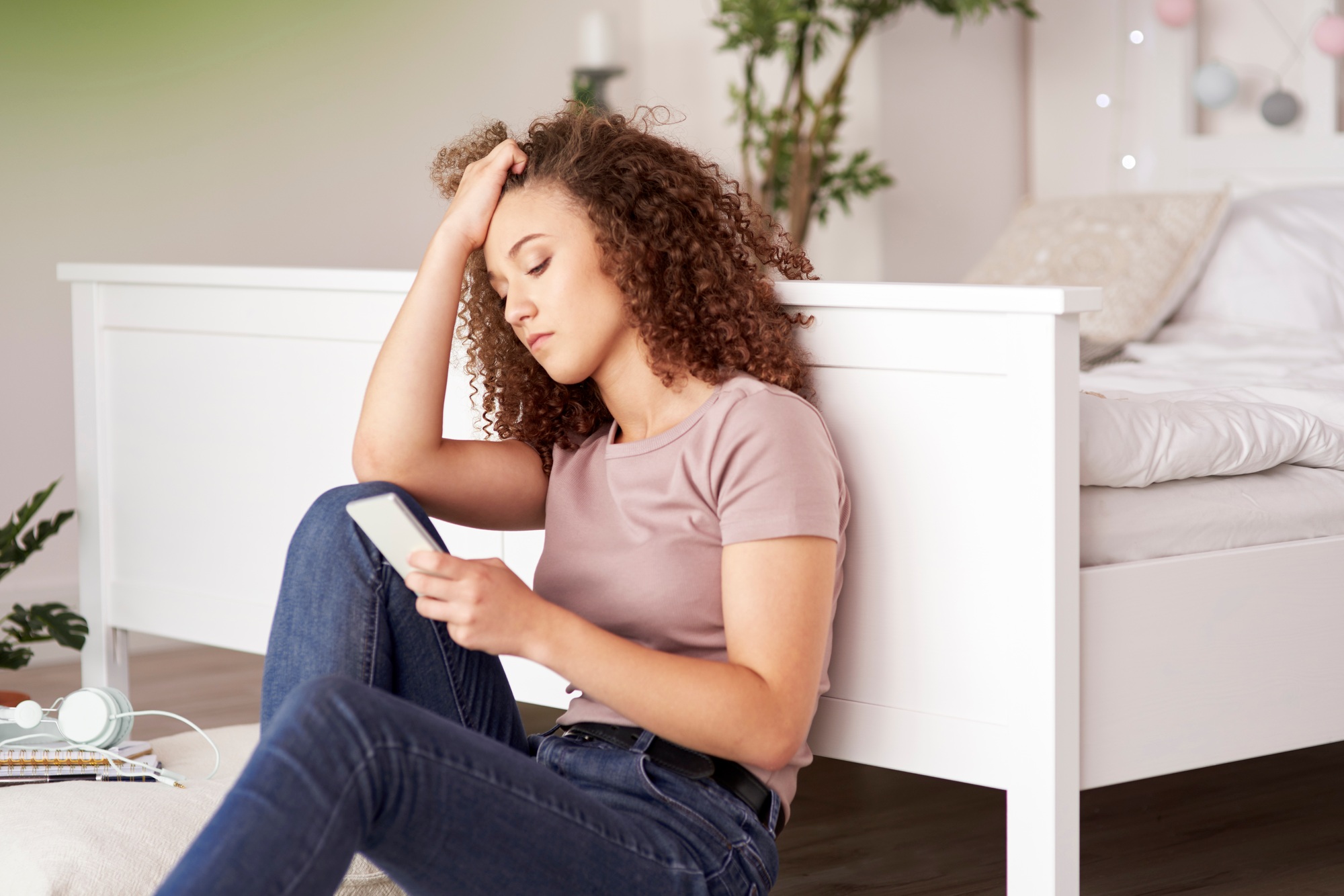 Worried teenage girl using mobile phone in her room