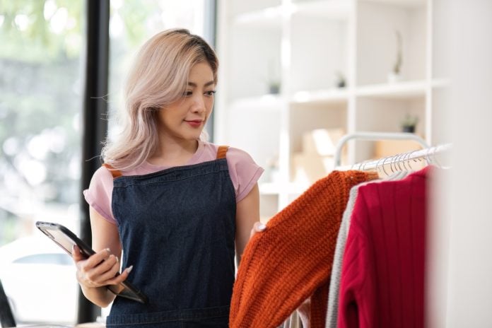 Young Female Entrepreneur Managing Online Clothing Business in Modern Boutique Setting